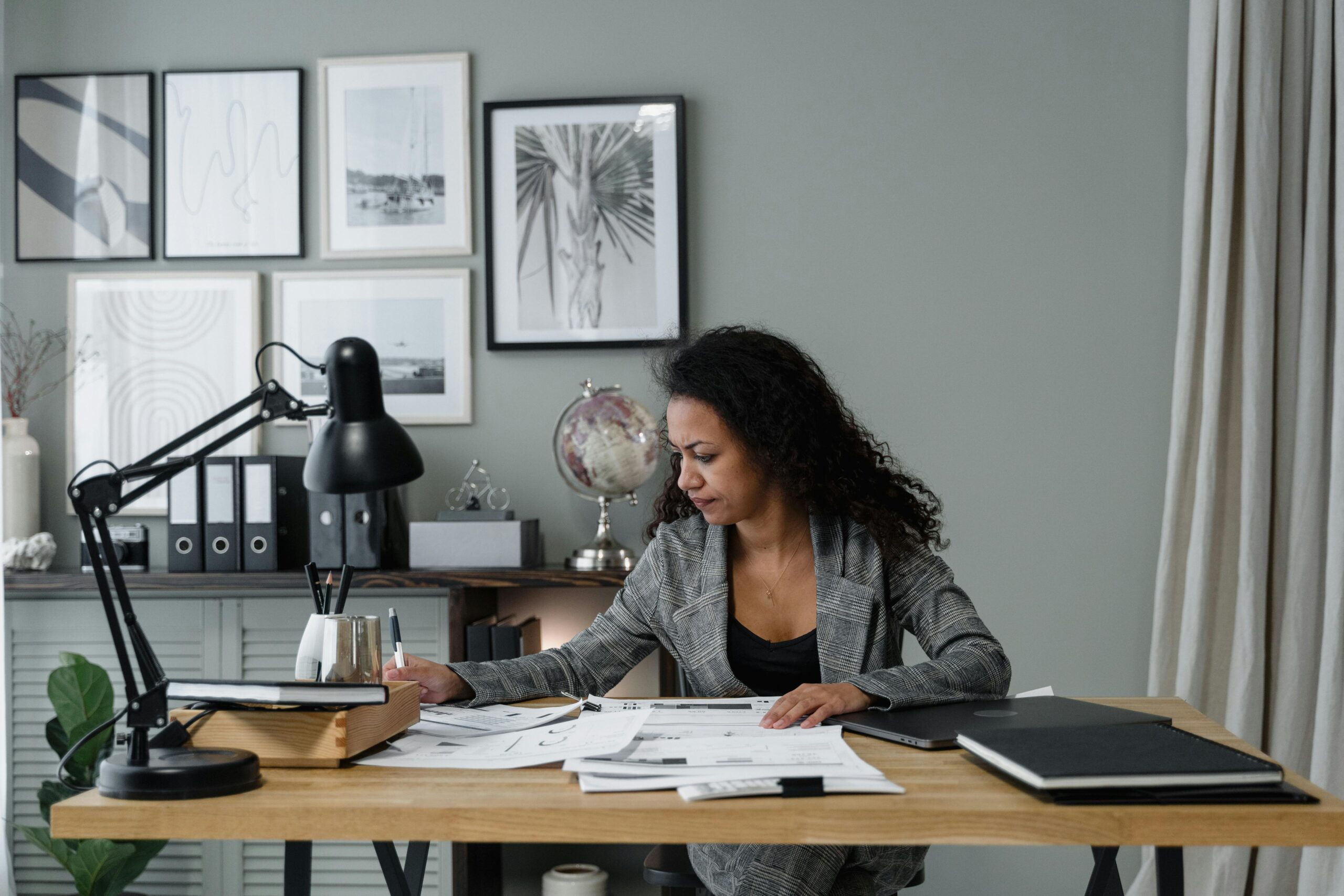 Businesswoman evaluates documents at a modern desk in a stylish office setting.